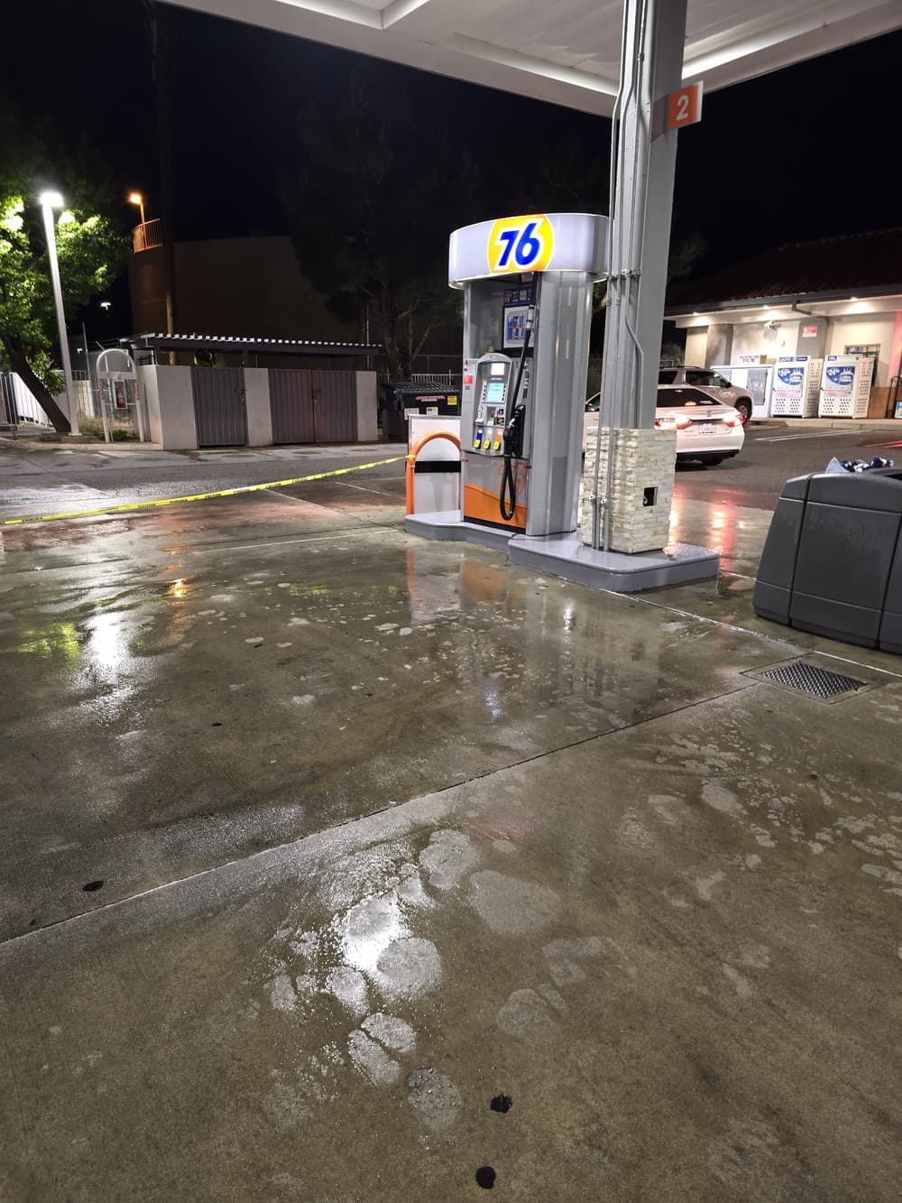 Gas station at night with wet pavement and illuminated 76 fuel pump.